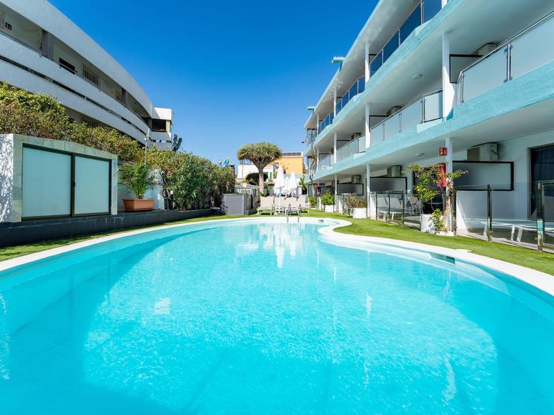 Moderner Hotelpool mit klarem blauem Wasser zwischen zwei Gebäuden bei sonnigem Himmel