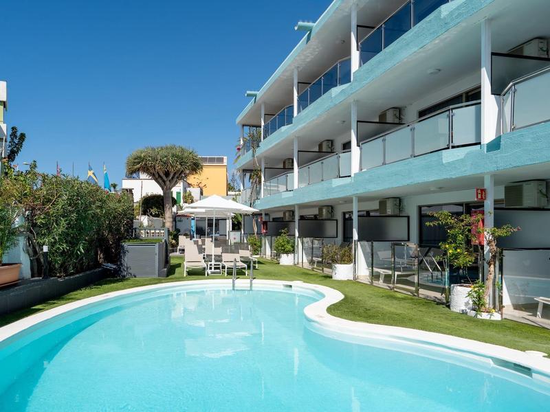 Moderner Hotelkomplex mit geschwungenem Pool und weißen Balkonen unter klarem Himmel