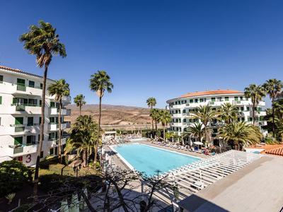 Gran piscina exterior con tumbonas en un complejo hotelero bajo un cielo azul claro.