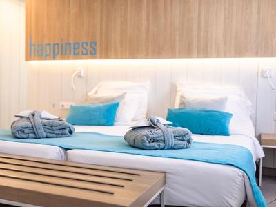 Habitación de hotel moderna con cama doble cómoda, acentos azules y decoración de madera en la pared.