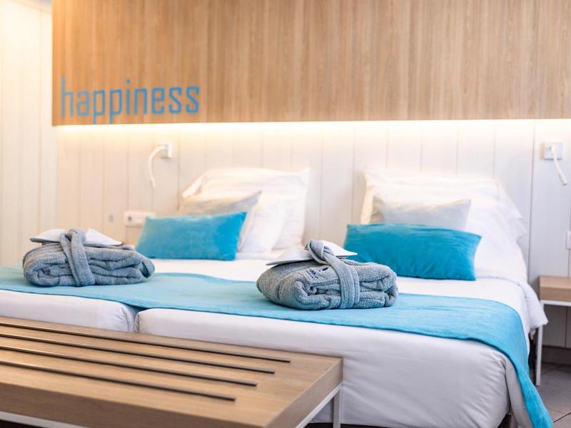 Habitación de hotel moderna con cama doble cómoda, acentos azules y decoración de madera en la pared.