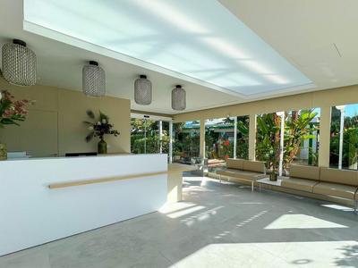 Hall d'hôtel lumineux avec comptoir blanc et grandes fenêtres laissant entrer la lumière du soleil.