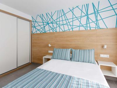 Chambre moderne avec lit double, oreillers rayés, panneau en bois et design mural bleu.