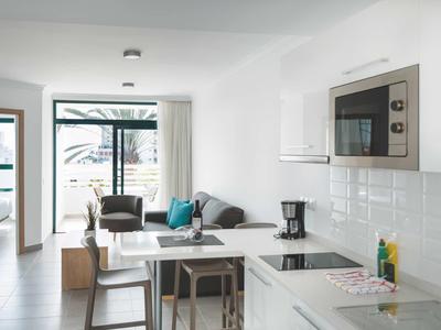 Cuisine et salon modernes et lumineux avec mobilier blanc et vue sur la terrasse.