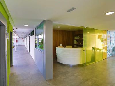 Hall d'hôtel moderne avec réception et long couloir aux tons neutres.