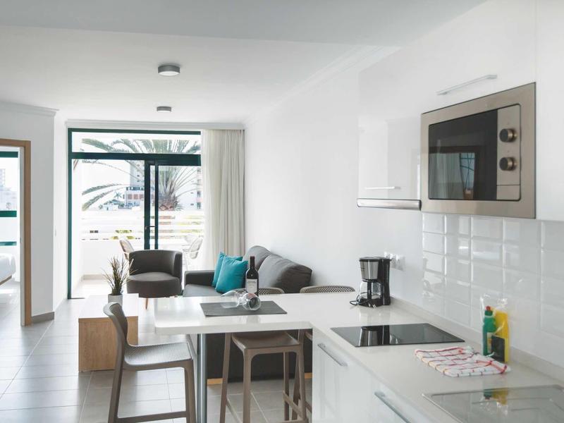 Cuisine et salon modernes et lumineux avec mobilier blanc et vue sur la terrasse.