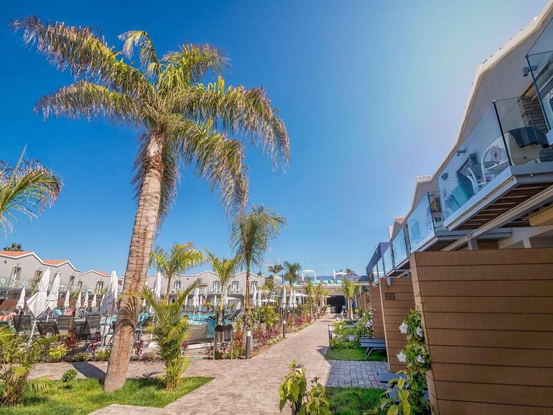 Ścieżka obsadzona palmami i budynkami z balkonami pod jasnym niebem