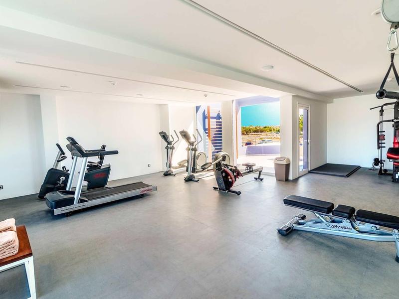 Nowoczesna siłownia z urządzeniami cardio i stanowiskiem do ćwiczeń siłowych, jasne okna z widokiem na miasto