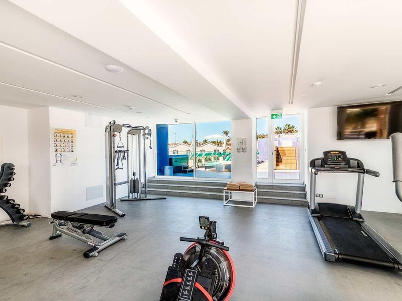 Jasna sala fitness z nowoczesnym sprzętem i dużymi oknami z widokiem.