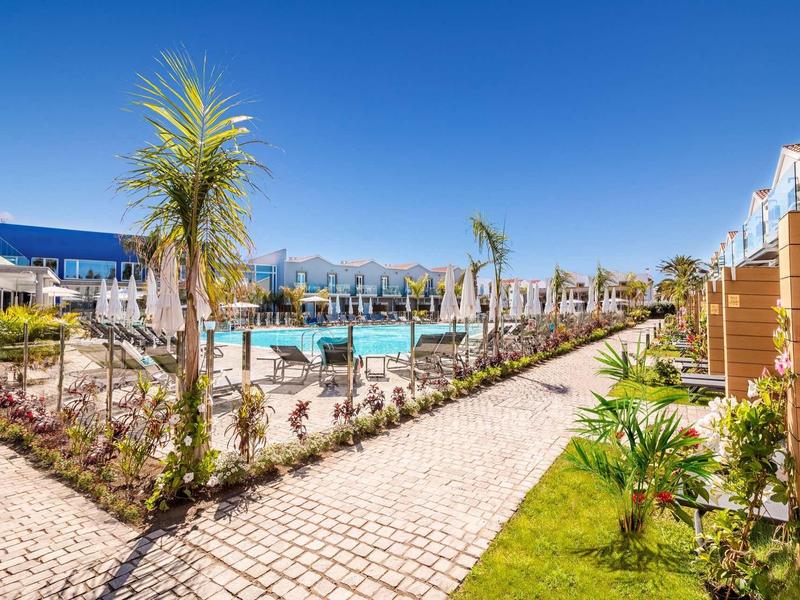 Nowoczesny basen na zewnątrz z palmami, miejscami do siedzenia i czystym niebieskim niebem.