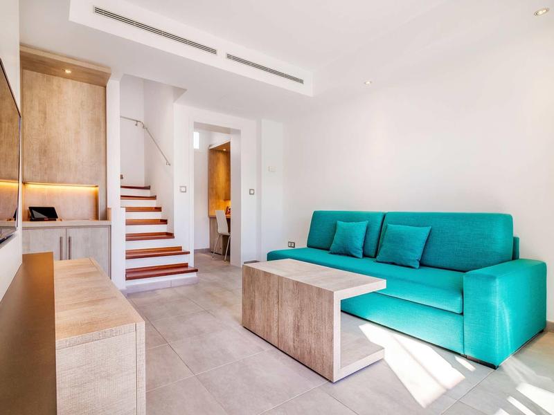 Nowoczesny salon z turkusową sofą i drewnianymi meblami w jasnym pomieszczeniu.