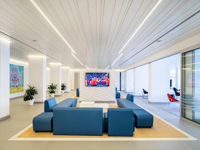 Espace lounge moderne d'hôtel avec sièges bleus, œuvres d'art et grande fenêtre.