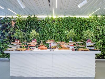 Buffet avec divers plats devant un mur de plantes vertes à l'intérieur.
