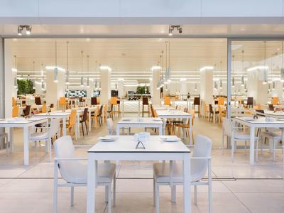 Restaurant lumineux avec tables et chaises blanches, design moderne et minimaliste.