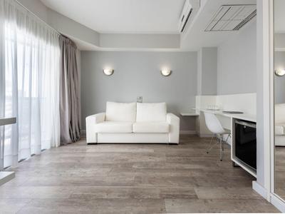 Chambre d'hôtel lumineuse et moderne avec canapé, grande fenêtre et design minimaliste.