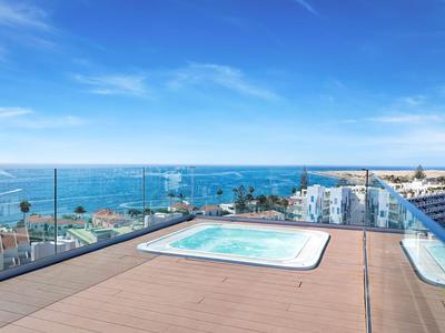 Piscina a sfioro sulla terrazza sul tetto con vista sul mare e edifici sotto un cielo azzurro