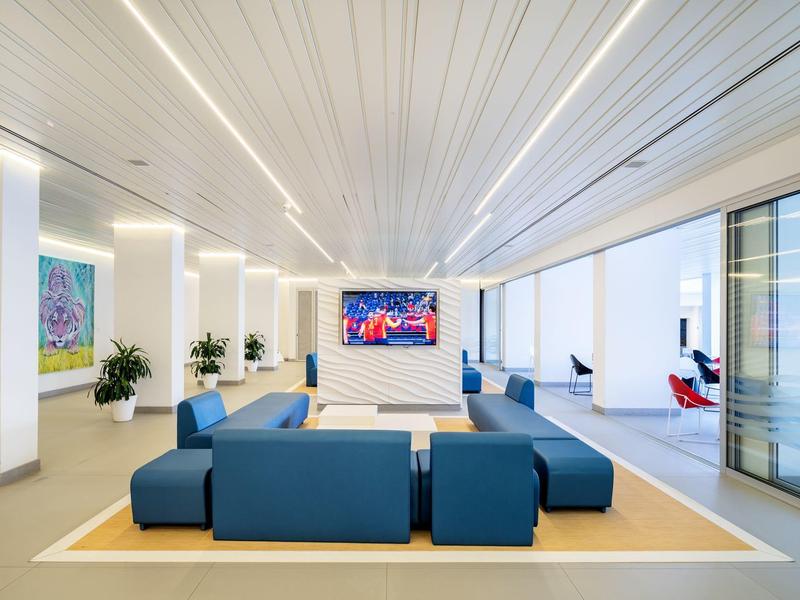 Espace lounge moderne d'hôtel avec sièges bleus, œuvres d'art et grande fenêtre.