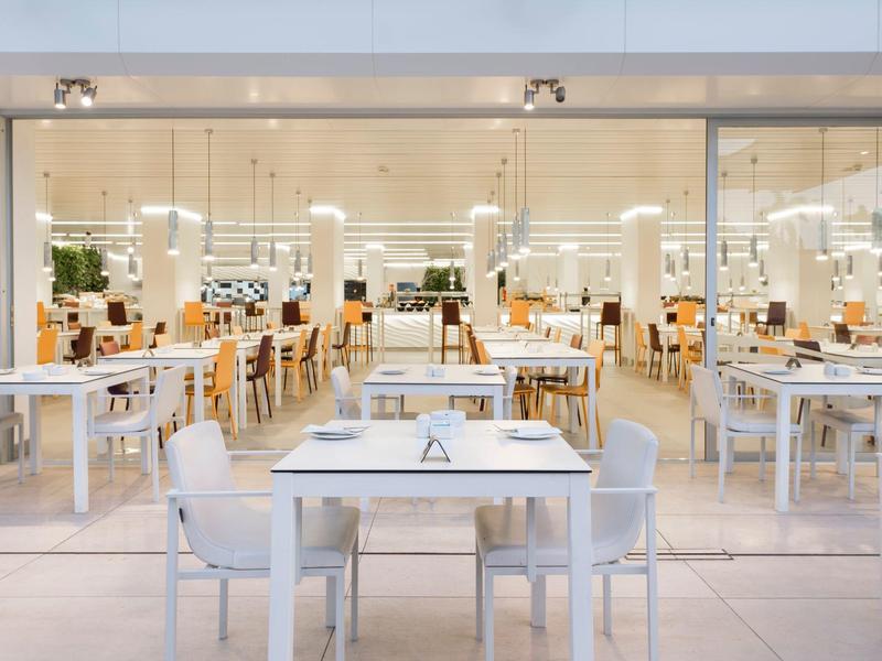 Restaurant lumineux avec tables et chaises blanches, design moderne et minimaliste.