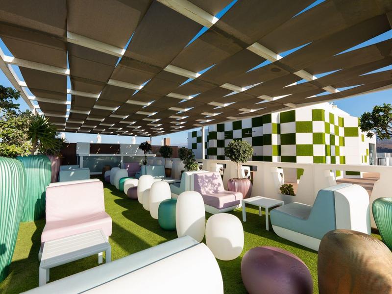 Salon extérieur avec sièges modernes colorés et espace couvert dans un hôtel.