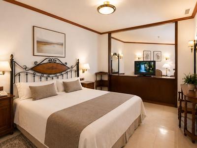Gezellige hotelkamer met een groot bed, klassiek meubilair en een wandspiegel.