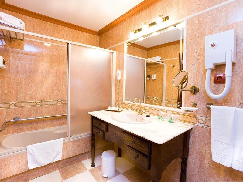Bright bathroom with bathtub, mirror, sink, and towels in a hotel room.
