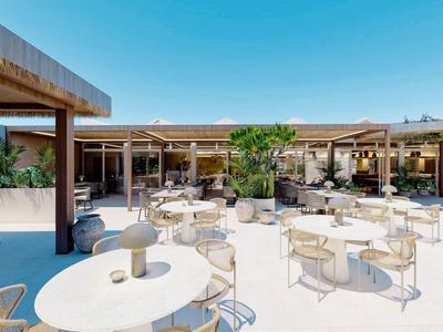 Buitengebied van een hotel met witte tafels, stoelen en een schaduwrijke lounge onder een blauwe lucht.