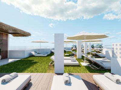 Modern rooftop terrace with sun loungers, umbrellas, and sea view under blue sky