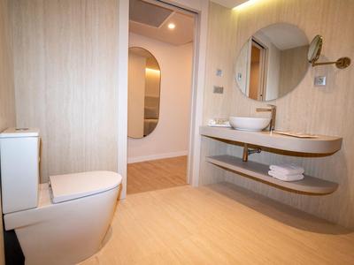 Baño moderno con inodoro blanco, espejo redondo y lavabo sobre estante de madera.