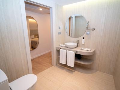 Jasna łazienka z okrągłym lustrem, umywalką, ręcznikami i toaletą w nowoczesnym stylu.