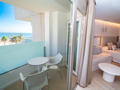 Balkon met witte tafel en stoelen naast moderne slaapkamer met zeezicht.