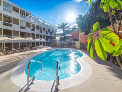 Nowoczesny basen na zewnątrz z leżakami i parasolami przed budynkiem hotelu.