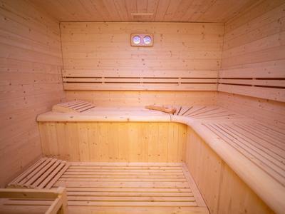 Innenraum einer Sauna mit Holzbänken und Wänden aus hellem Holz.