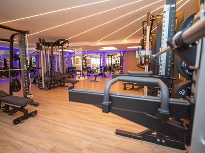 Modernes Fitnessstudio mit verschiedenen Trainingsgeräten und Holzfußboden in einem Hotel.