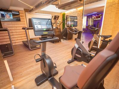 Moderne Fitnessgeräte in einem gemütlichen, gut beleuchteten Trainingsraum eines Hotels.