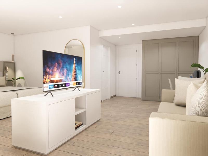 Modern ingerichte woonkamer met bank, tv op witte kast en lichte houten vloer.