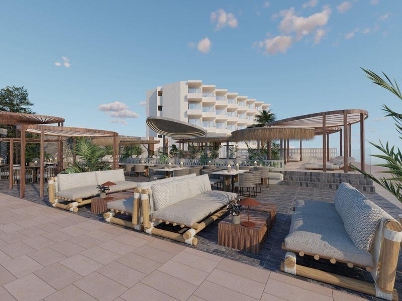 Área exterior moderna con asientos cómodos y vista a un edificio de hotel bajo un cielo despejado.