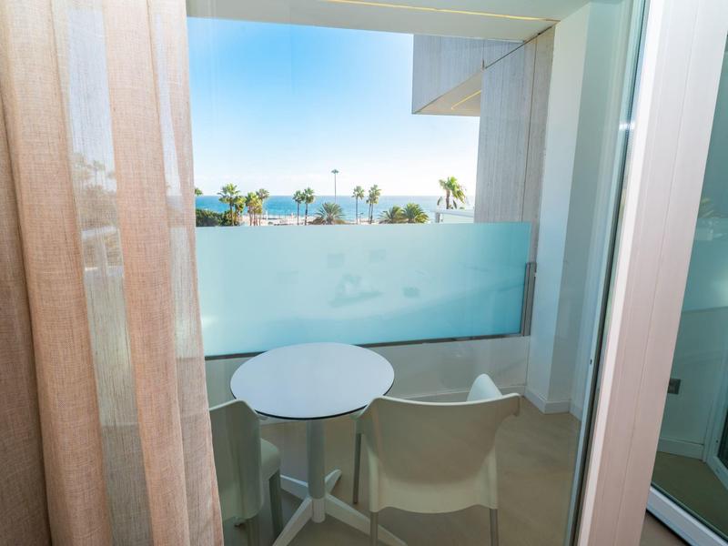 Balcón con una pequeña mesa redonda y dos sillas con vista al mar.