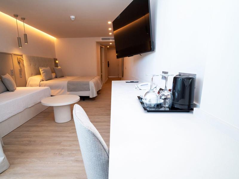 Habitación de hotel moderna con dos camas, escritorio y TV montada en la pared.