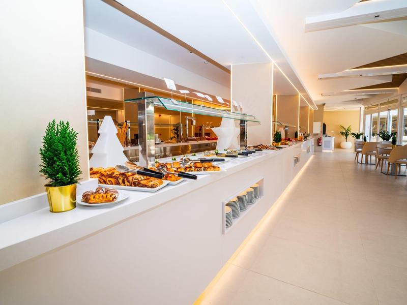 Área de desayuno moderna con buffet y pasteles en un interior luminoso y elegante.