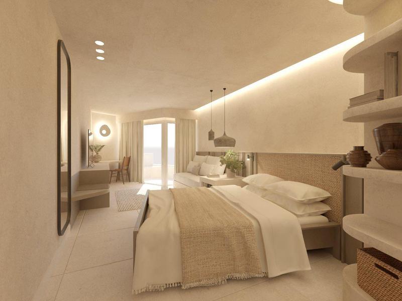 Licht hotelkamer met tweepersoonsbed, open rek en bureau bij het raam.