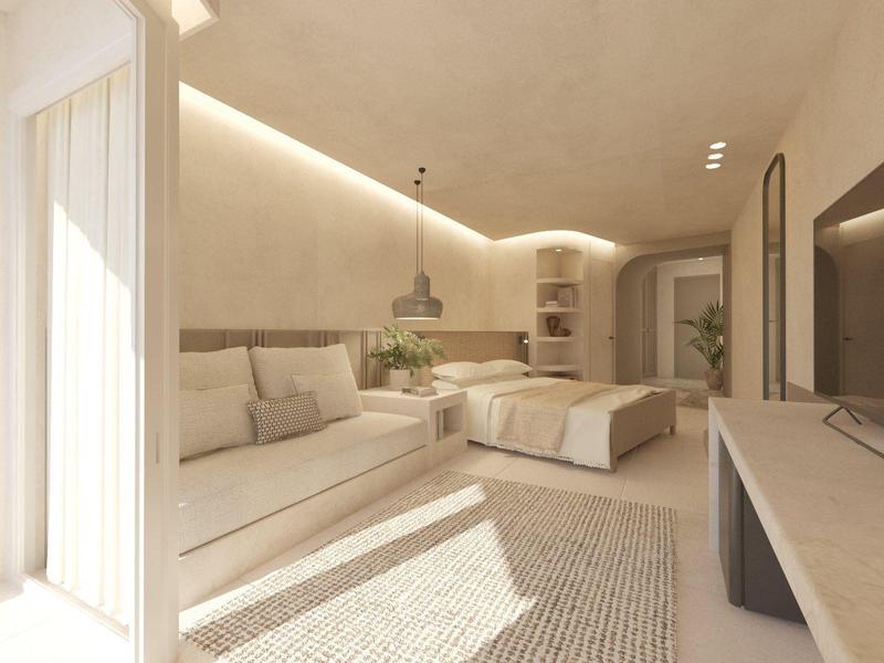 Modern ingericht hotelkamer met bank, bed, vloerkleed en veel natuurlijk licht.