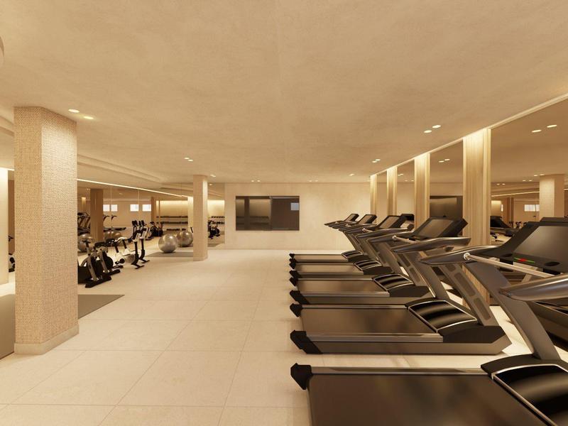 Ruime fitnessruimte met loopbanden en moderne apparatuur in lichte, warme kleuren.