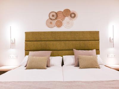 Moderne hotelkamer met twee bedden, olijfgroene hoofdbord en decoratieve wandaccenten.