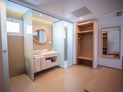 Lichte badkamer met twee wastafels, grote spiegel en open kledingkast.