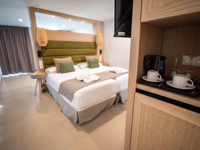 Modern eingerichtetes Hotelzimmer mit Doppelbett, Kaffeestation und Vorhängen.