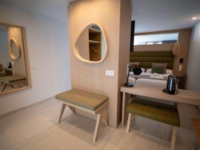 Moderner Hotelzimmerbereich mit Sitzbank, Schreibtisch, Spiegel und bequemen Stühlen in neutralen Farben.