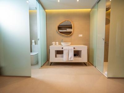 Modernes Badezimmer mit weißem Waschtisch, rundem Spiegel und Glaswänden.