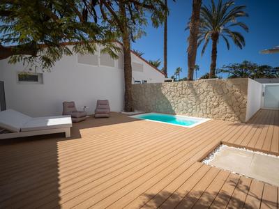 Moderner Poolbereich mit Holzterrasse, Liegestühlen und Palmen im sonnigen Außenbereich.