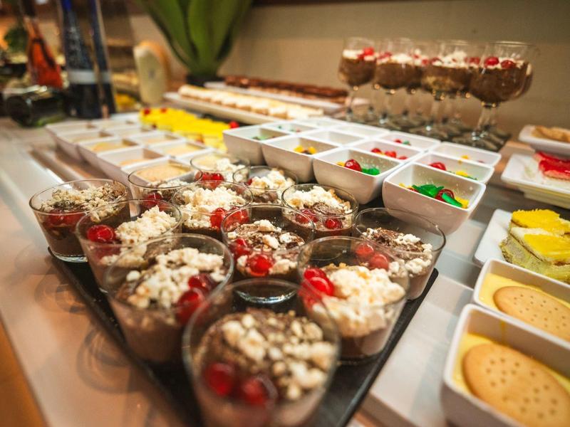 Verschillende desserts en zoetigheden in glazen en kommen gepresenteerd op een buffet.