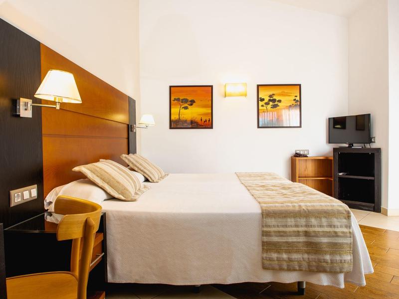 Lichte hotelkamer met twee bedden, houten meubels en wanddecoratie.